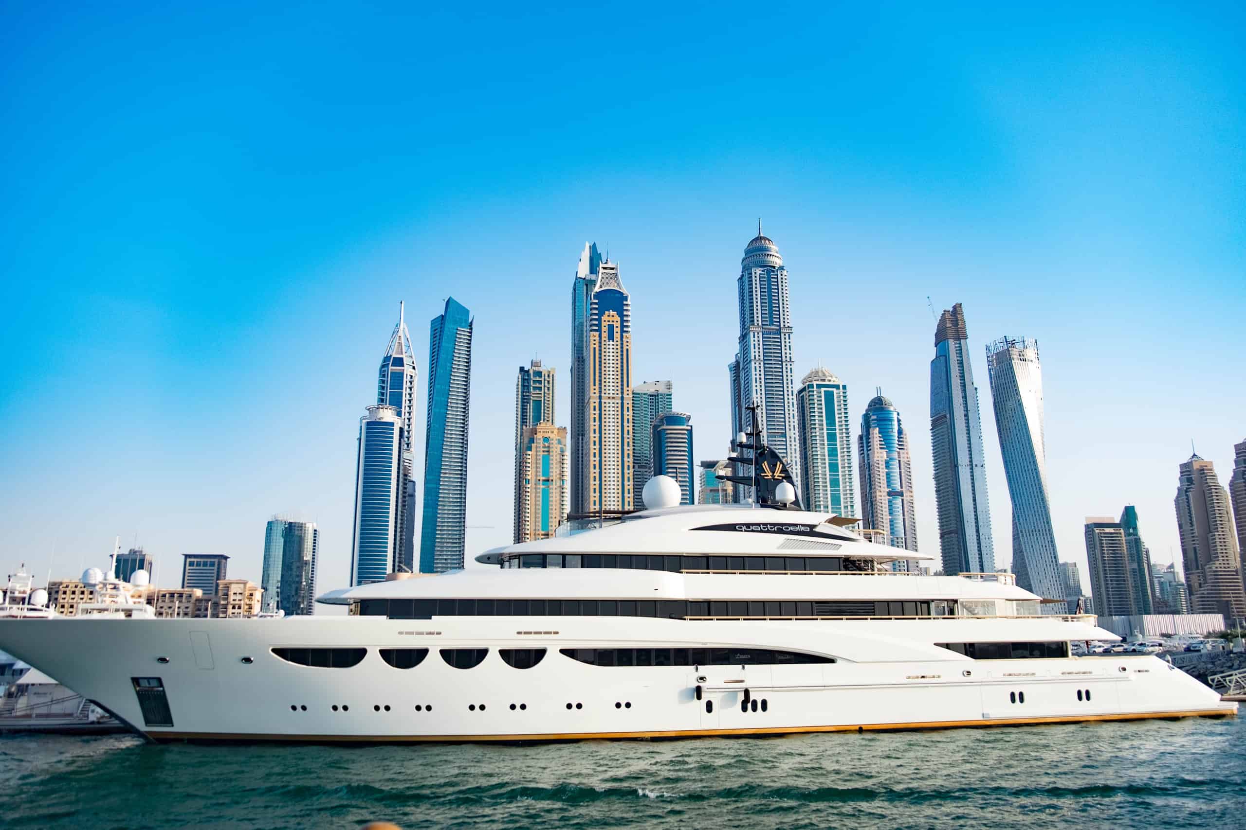 An opulent superyacht in Dubai marina with skyscraper buildings backdrop